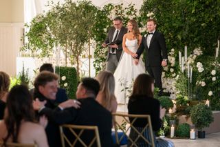 Taylor Haag (center) and Daniel Hastings (right) stand at the altar with their officiant in front of a seated crowd, in 'Love Is Blind' season 8.