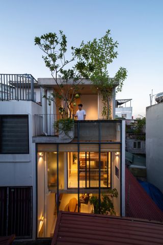 TH House with a person standing on a balcony of a two floor house complex.