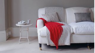 pale grey living room with white sofa draped in bright red throw to add colour