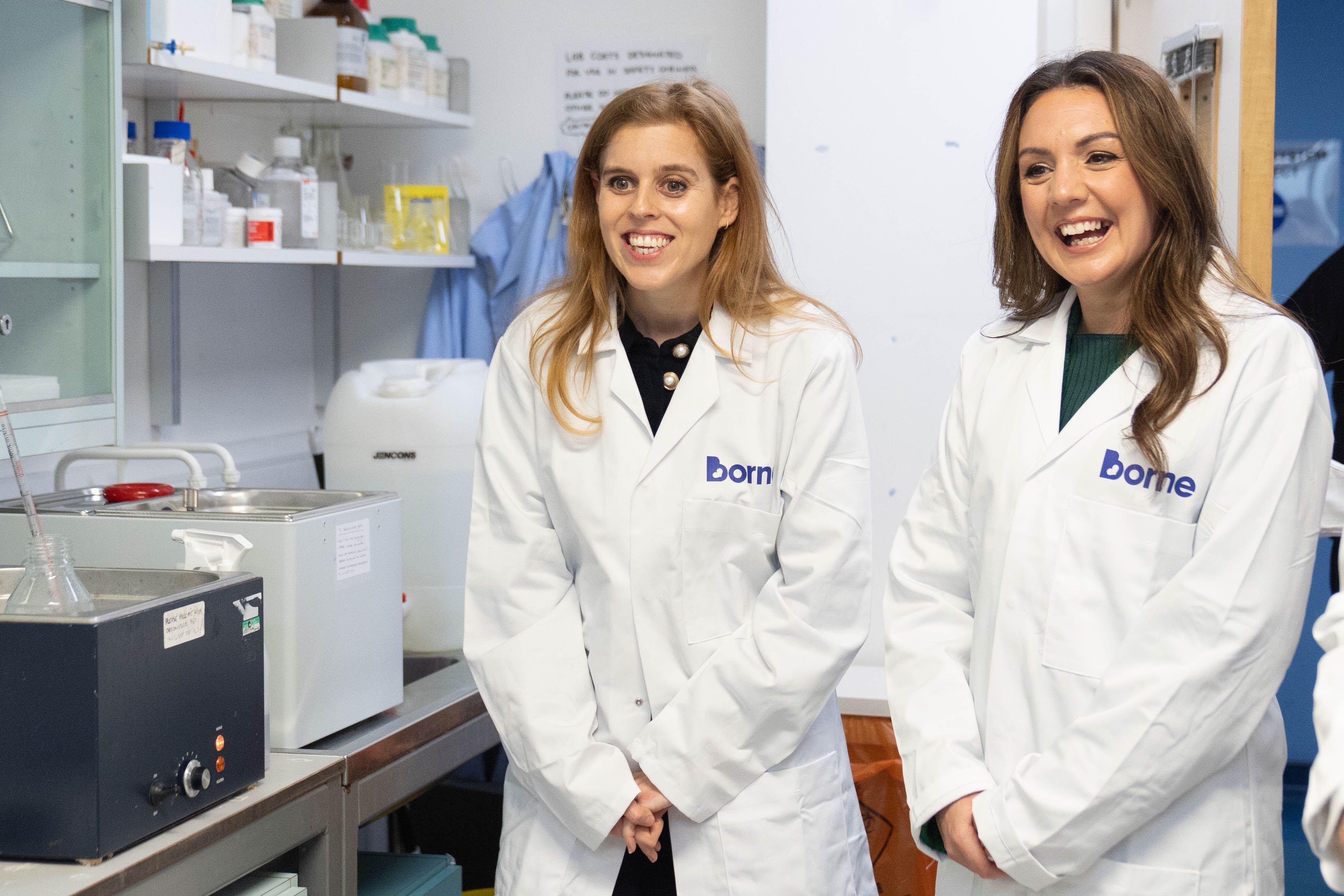 Princess Beatrice and a woman wearing white lab coats and smiling