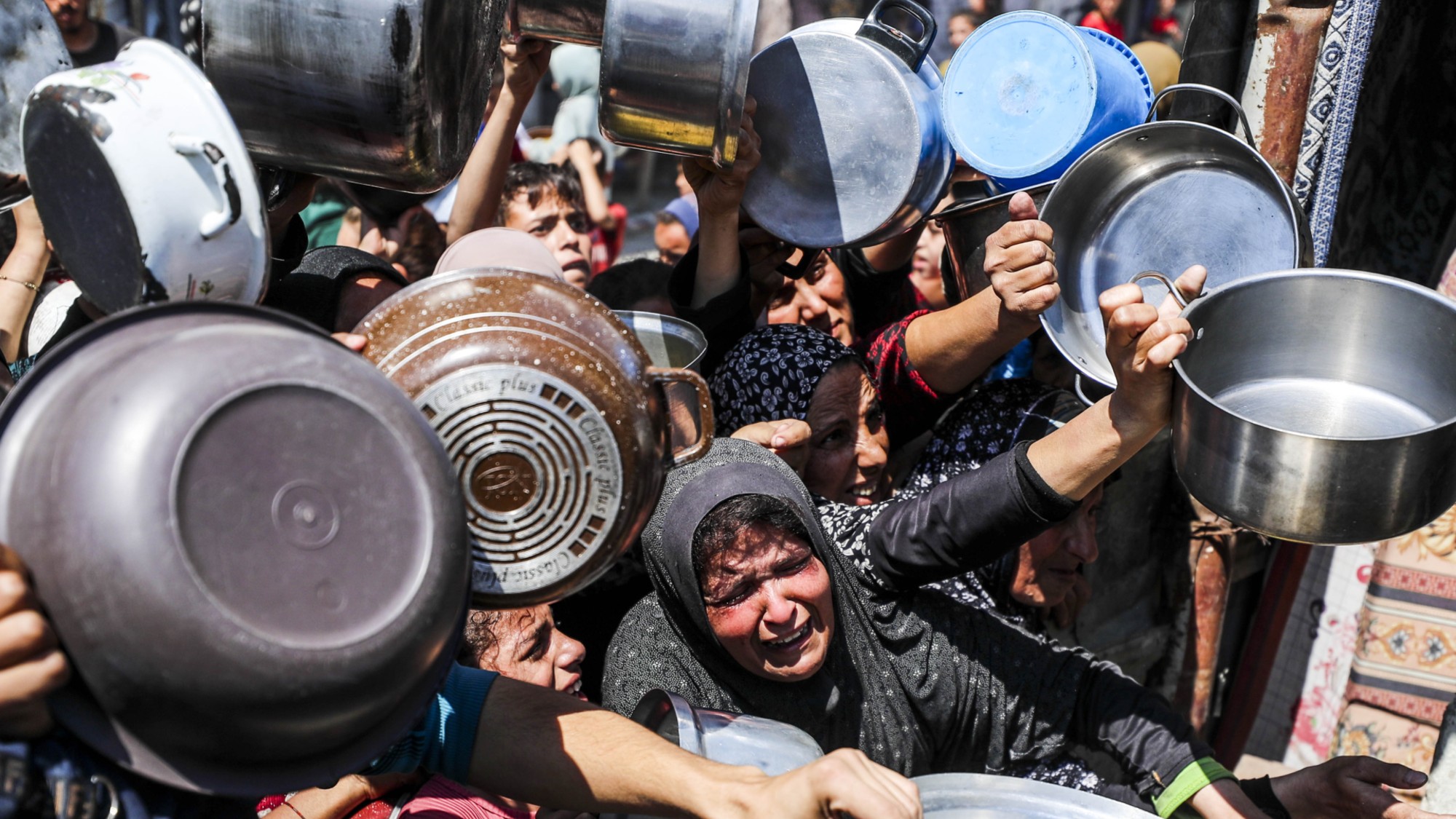 Displaced Palestinians receive hot meals distributed by aid organizations in Jabalia refugee camp of Jabalia, Gaza