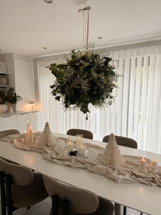 Hanging floral centerpiece over a white Christmas table setting in a white dinning room