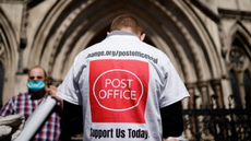 A person wearing a T-shirt with a Post Office logo on the back outside the Royal Courts of Justice
