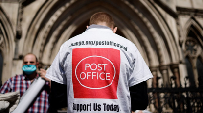 A person wearing a T-shirt with a Post Office logo on the back outside the Royal Courts of Justice