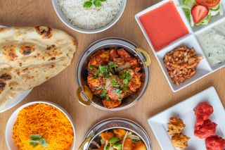 A table spread with assorted Indian dishes such as pilau rice, naan bread, and pakora.