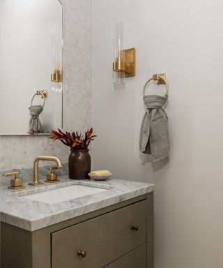 neutral bathroom with marble countertop and marble tiled wall, brass hardware, mirror