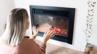 A woman warming her hands by a fireplace