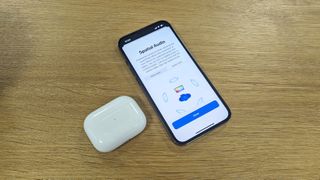 A pair of AirPods Pro next to an iPhone showing a screen saying that Spatial Audio is active