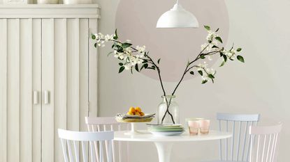 White dining room with round table, pastel chairs and paint affect on wall