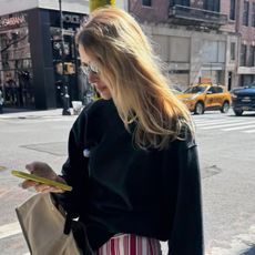 Courtney wears a black sweatshirt, and high sport red stripe pants.