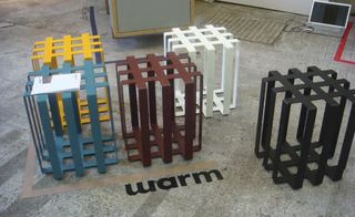 Floor view, Grey floor with word 'warm' in black letters, coloured metal style crate stools, neutral door mat, computer screen, bottom of wooden unit