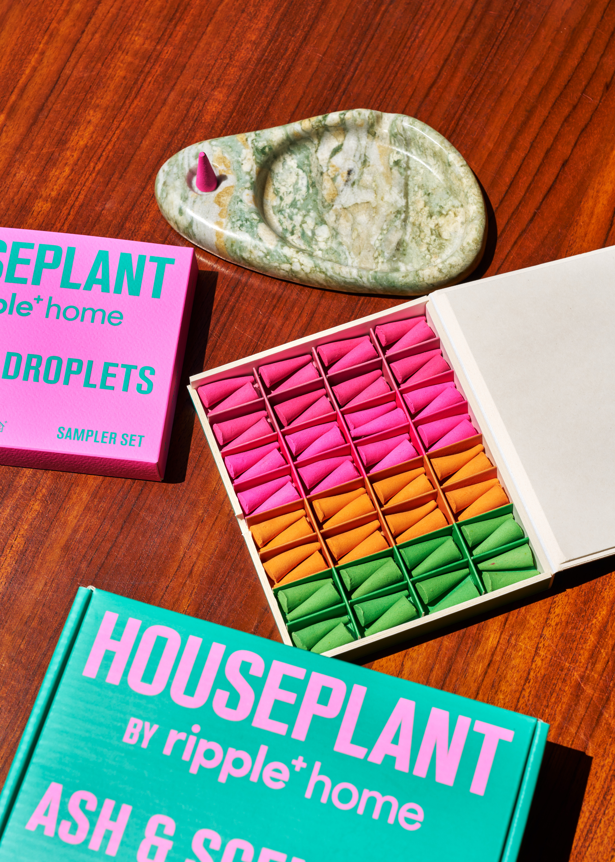 A box of red, pink, orange, and green incense cones near a large marbled holder