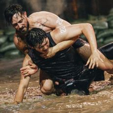 two men (justin harvey and another contestant) wrestle in a pit of shallow water, in 'physical 100' season 2