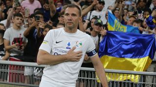Andriy Shevchenko poses next to the Ukraine flag at an exhibition match in Milan.