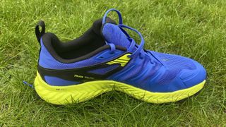 Closeup of single Inov8 TrailTalon all-terrain running shoe, on grass, showing instep
