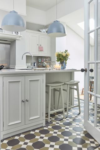 Victorian style tiling showing the best kitchen flooring in a neutral scheme with blue pendant lighting.