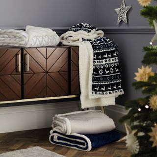 grey wall brown wooden cabinet and designed fleece blankets