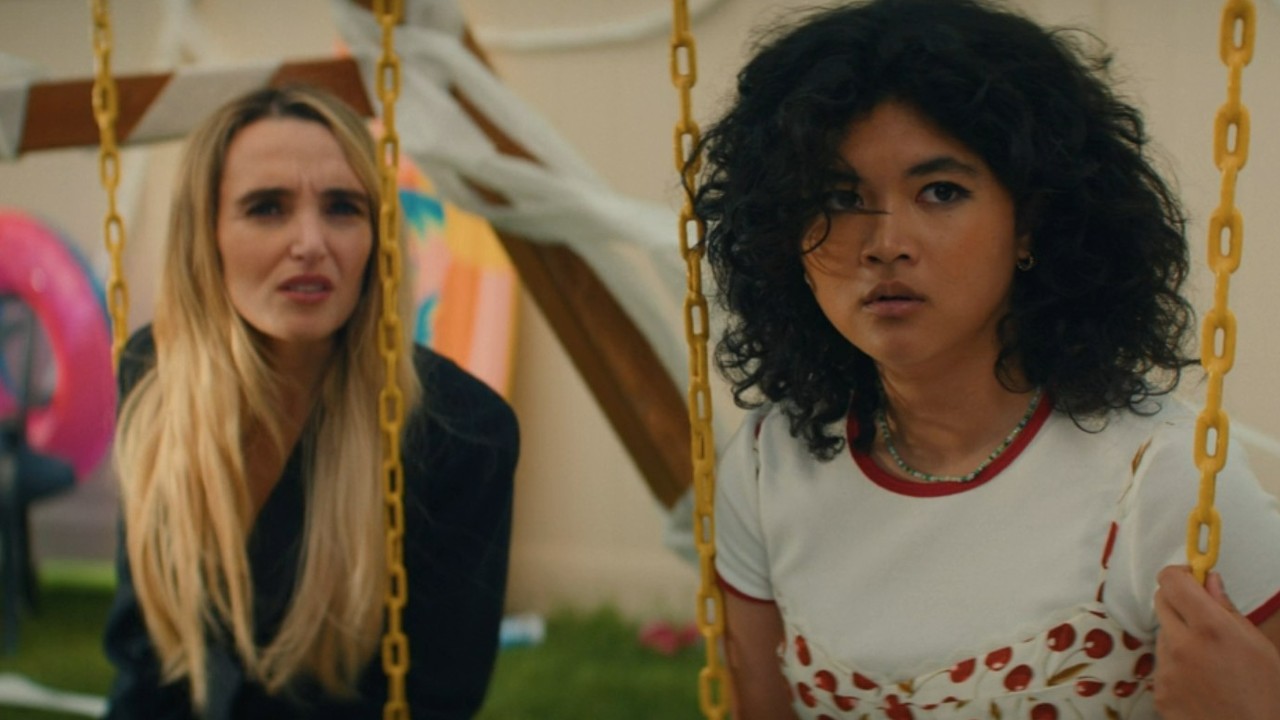 Chloe Fineman and Sam Morelos looking shocked on a swing in Summer of 69