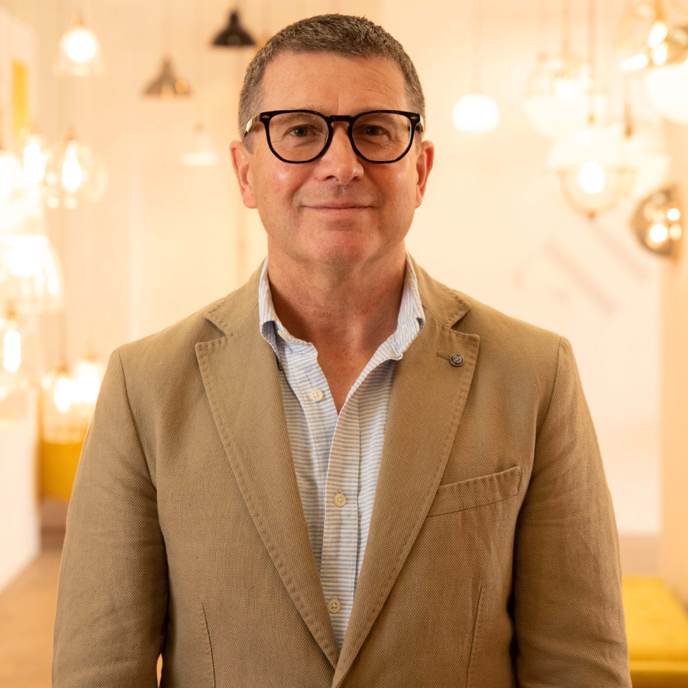 male with short hair wearing glasses, beige suit jacket and striped shirt