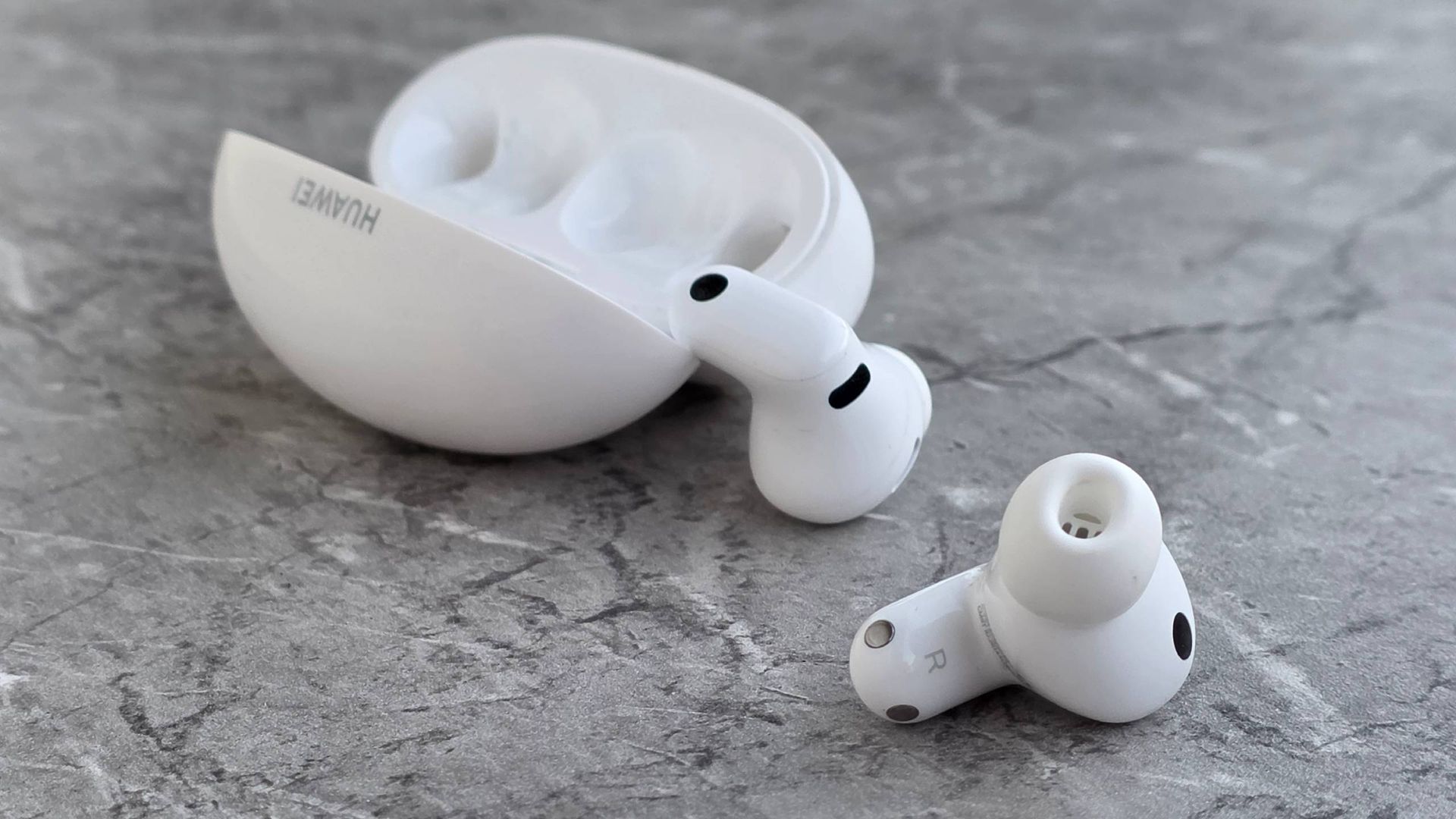 The Huawei FreeBuds Neo buds and case on a marbled surface.