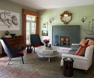living room with pale green walls gray slate fireplace and armchairs
