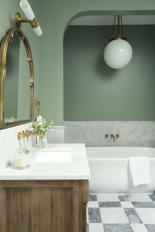 Pale green bathroom with white marble sanitary ware and arched wall