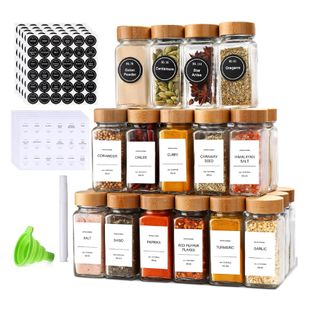 A set of 24 spice jars with labels stacked like a pyramid. Six on the bottom row, five on middle layer, four on top. To the left are graphics of the black round and white square labels the set comes with as well as green funnel for refilling spices.