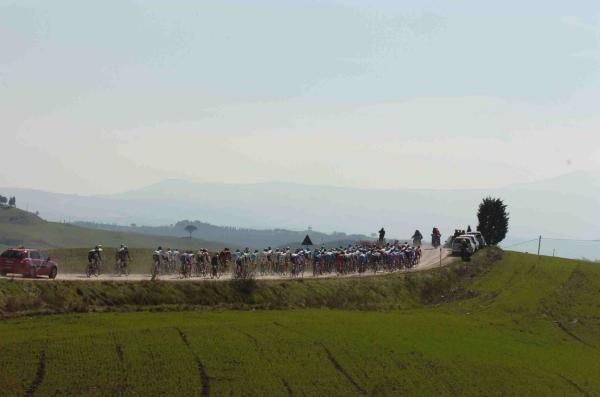 The peloton fills the dirt roads