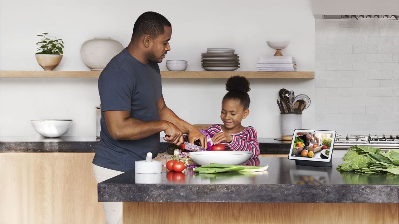 voice control a father and child preparing food in a kitchen with a smart hub showing a video recipe