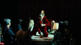 Zoe Saldana singing and dancing on a table in Emilia Perez