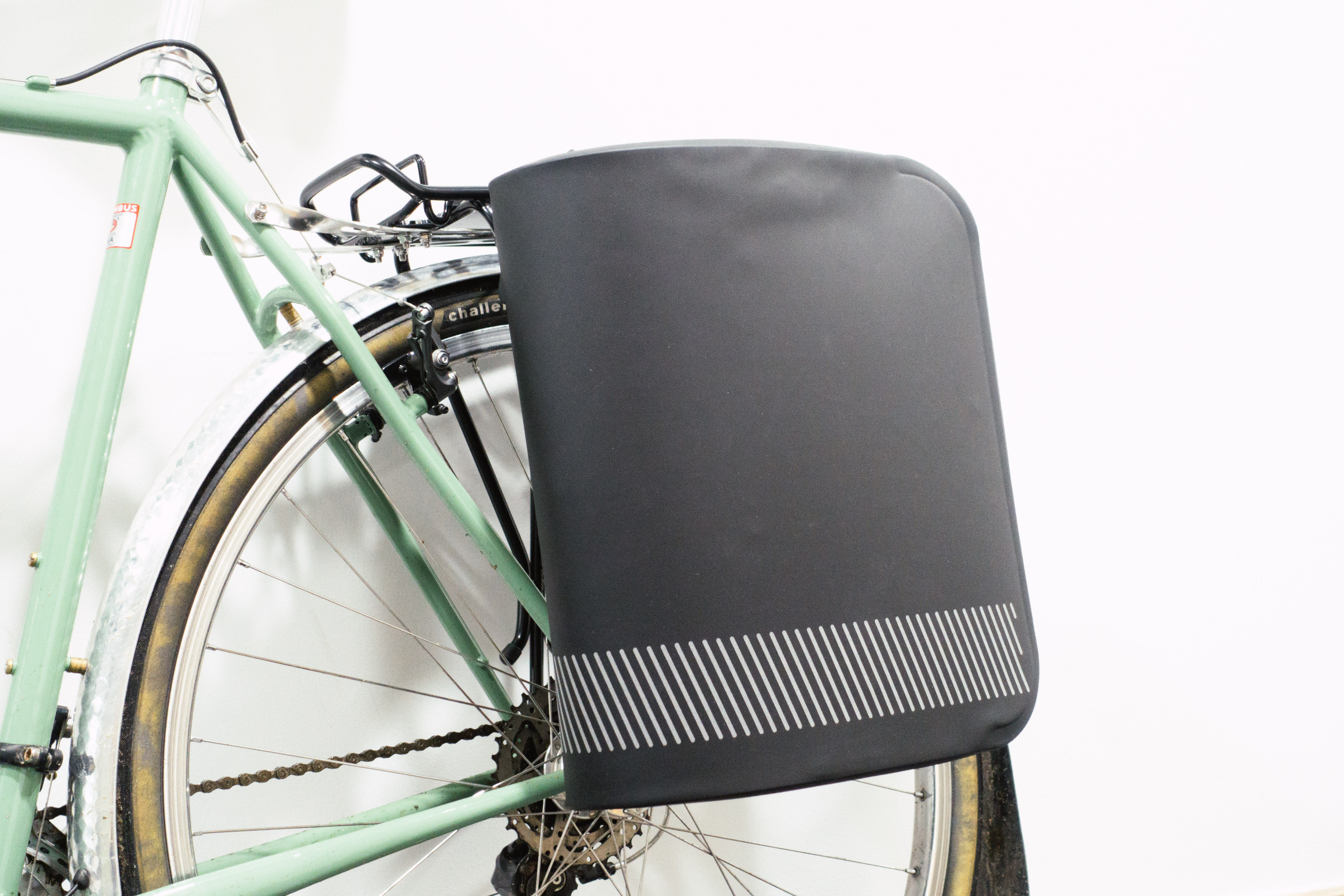 An aerodymanic pannier mounted to a green bike against a white background