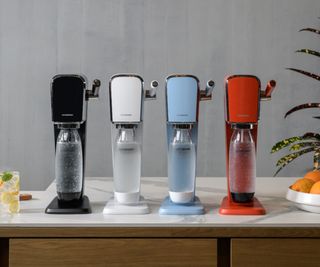 SodaStream Art in black, white, blue, and red, lined up on a countertop