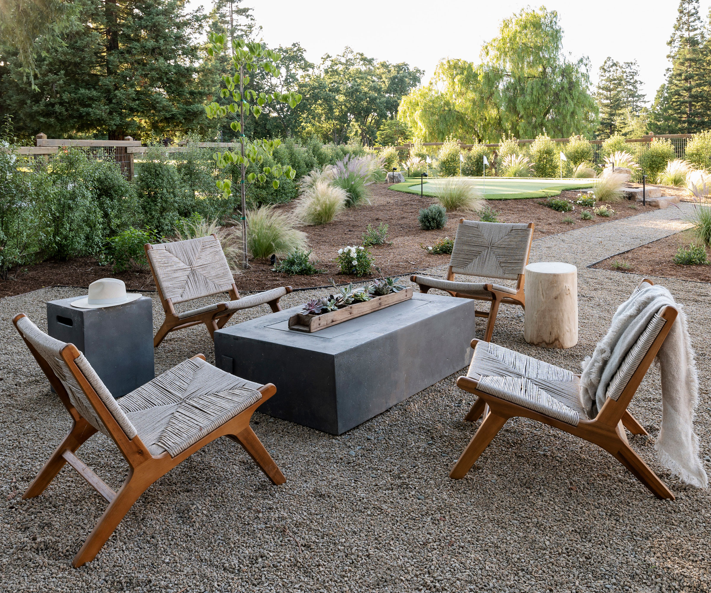 landscaped back yard design with gravel, fire table, garden chairs, path and planting