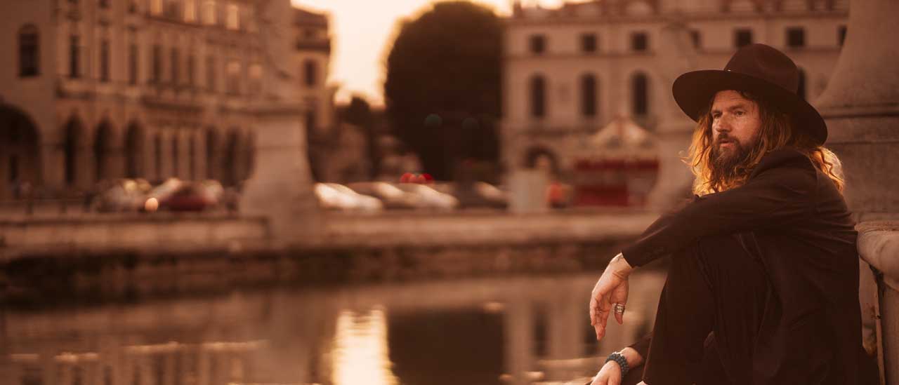 Jay Buchanan sitting by a canal, dangling his foot in the water