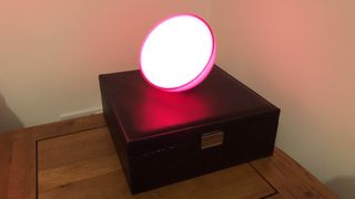 The Philips Hue Go Portable Light illuminated on a bedside cabinet
