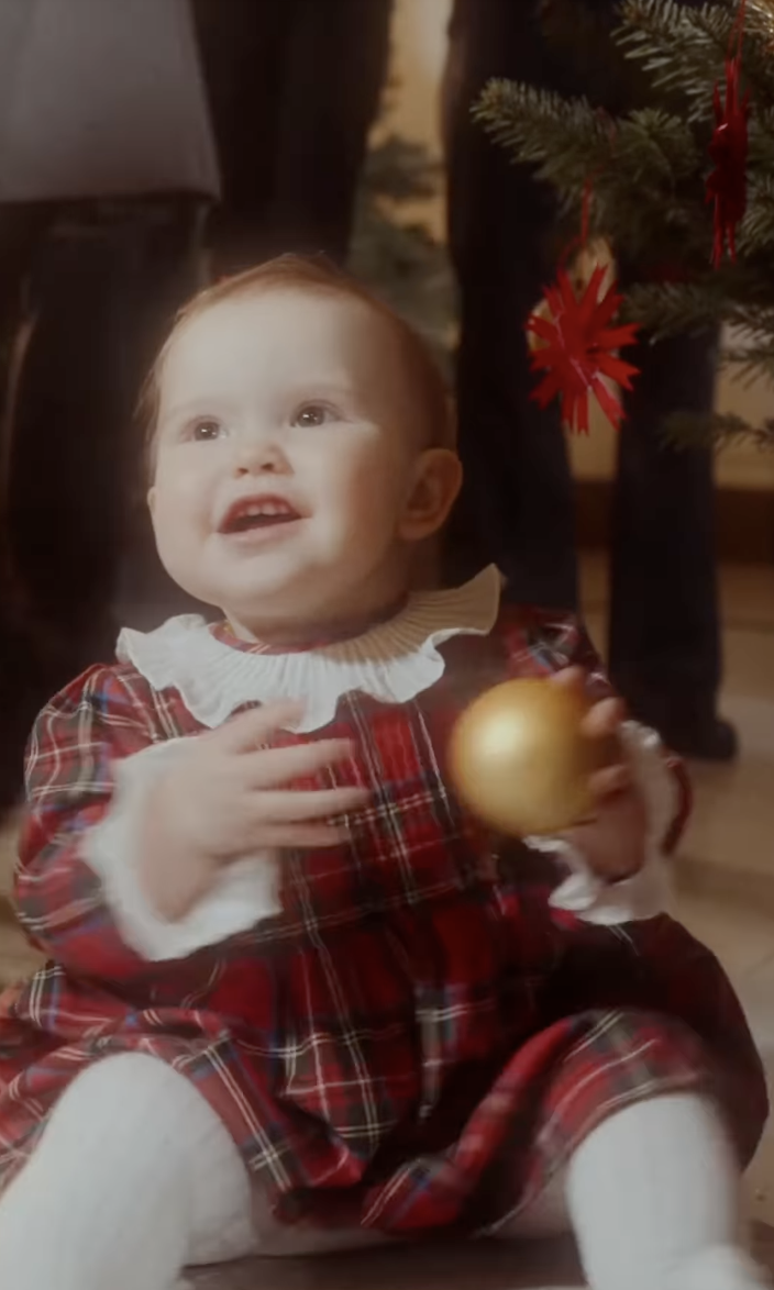 Princess Ines wearing a plaid dress holding an ornament