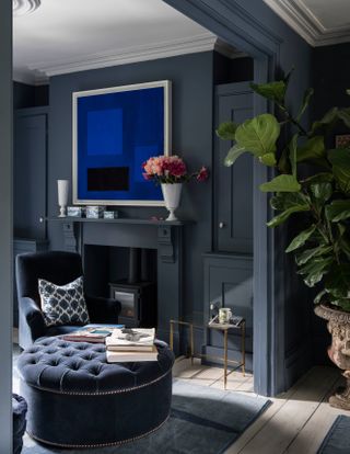 Dark blue living room with fireplace and foot stool