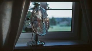 Bedroom fan propped up against an open window