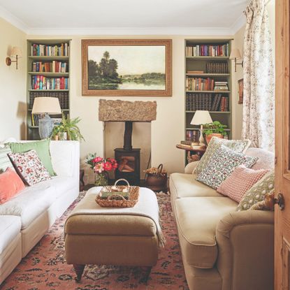 A narrow living room with two sofas facing each other, bookcases built into alcoves and a wood burning stove in between