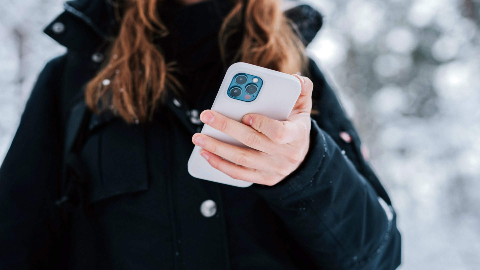 A person holds an iPhone in a white case.