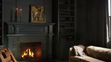 black living room with roaring fire and brown sofa