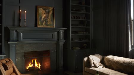 black living room with roaring fire and brown sofa