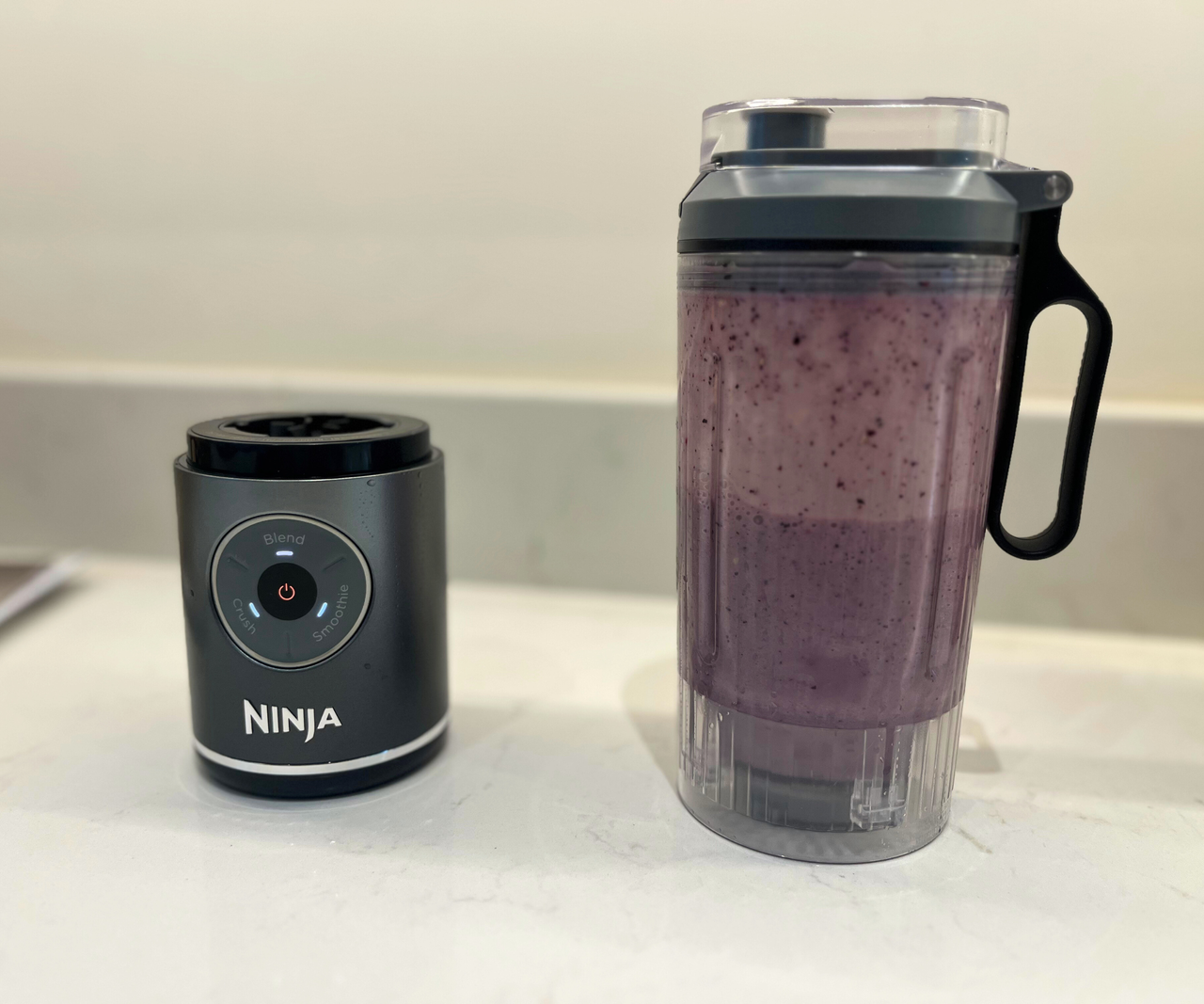 The pitcher of the Ninja Blast Max is filled with purple smoothie, separated from the base