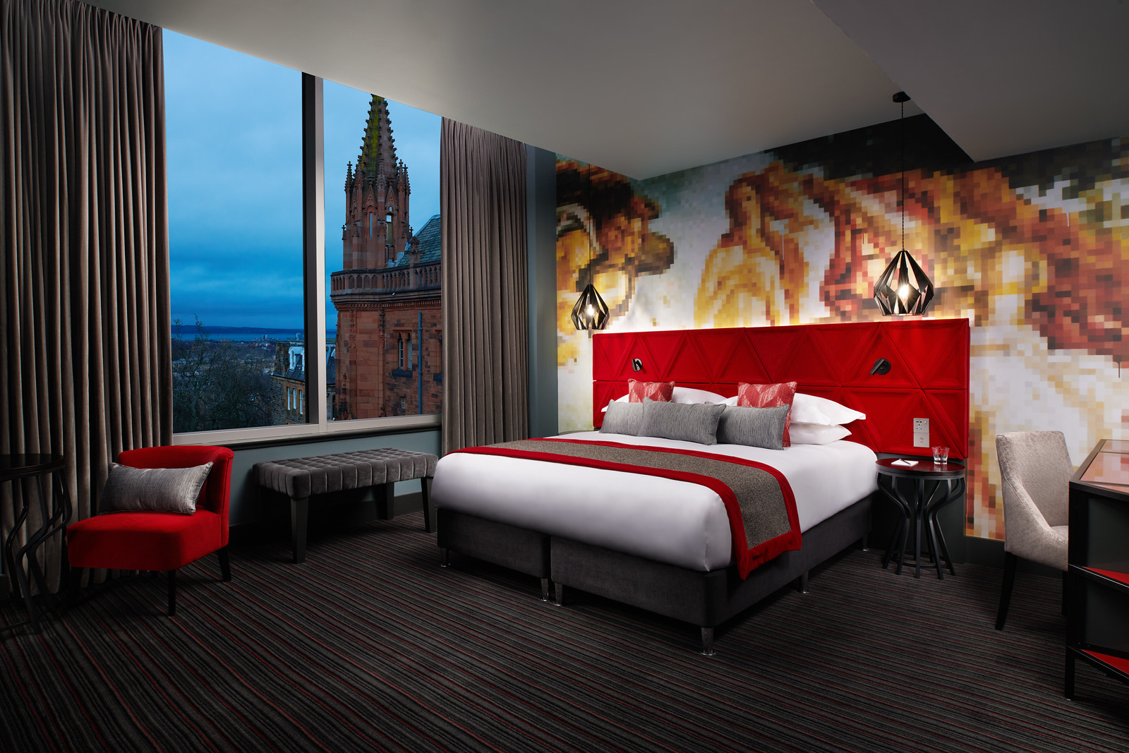 A room at Malmaison Edinburgh City with a colorful mural on the wall and red headboard