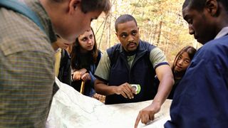 what are contour lines on a map: a hiking guide shows his group the route on the map before setting off