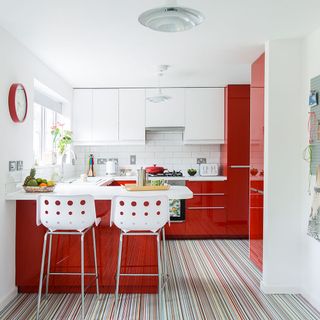 kitchen with white wall red cabinets and designed floor