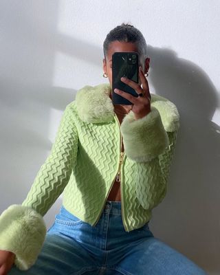 Woman wearing skinny jeans and lime green cardigan.