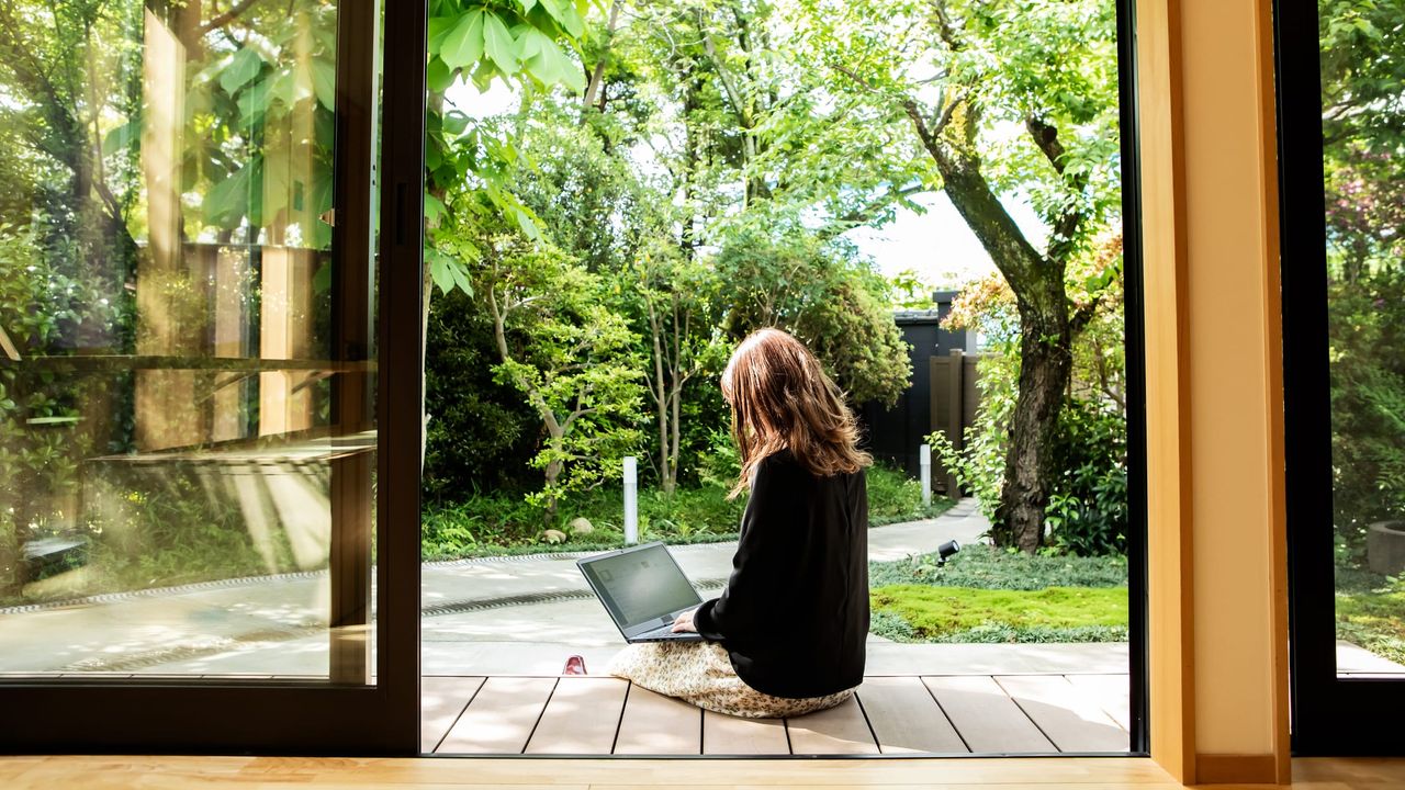 A woman sits outside as she does work on her laptop