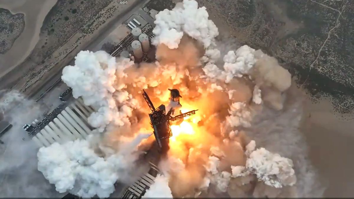 a large silver-and-black rocket launches above a plume of fire