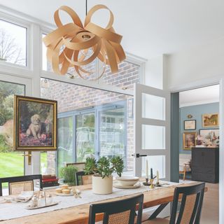 A dining room with a statement ribbon-like pendant light above a long rectangular dining table